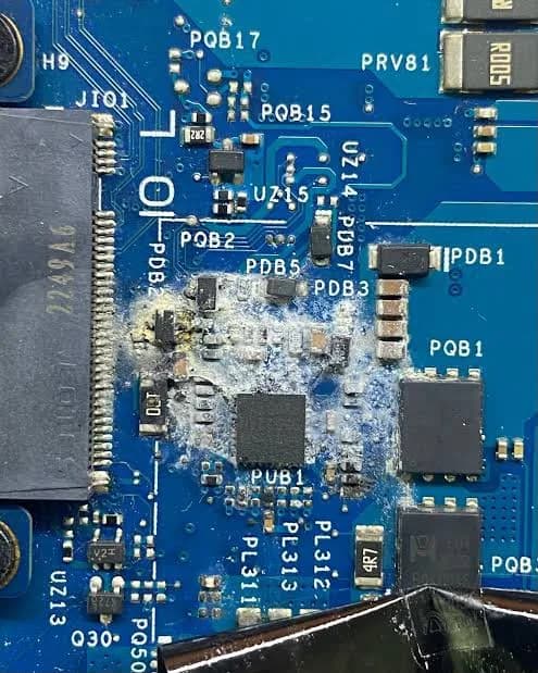 Detalhe de uma placa de circuito azul com crosta esbranquiçada de oxidação em volta dos componentes.